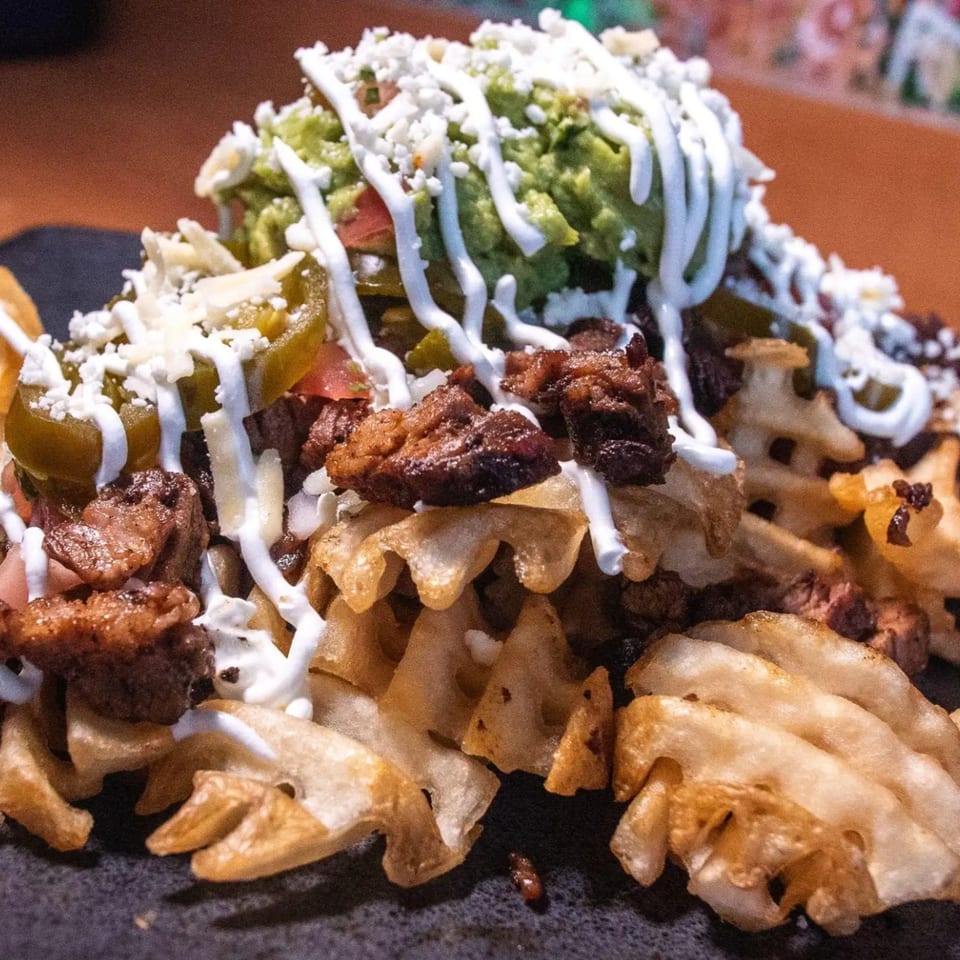 Taco Verde's waffle fries loaded with carne asada, guacamole, sour cream, jalapeños, and cheese.